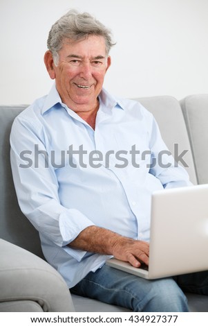 Senior adult smiling while using laptop