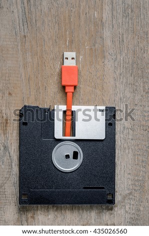 Used floppy diskettes with orange USB cable Plug on wooden background,design for technology concept