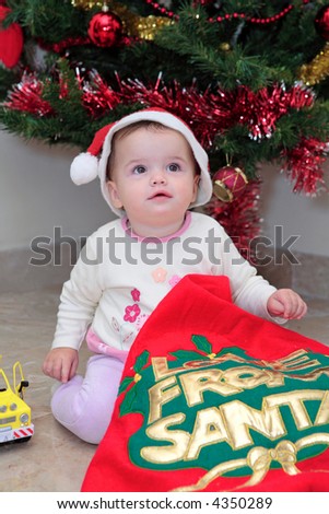 Baby girl opening Christmas Presents by the Xmas tree