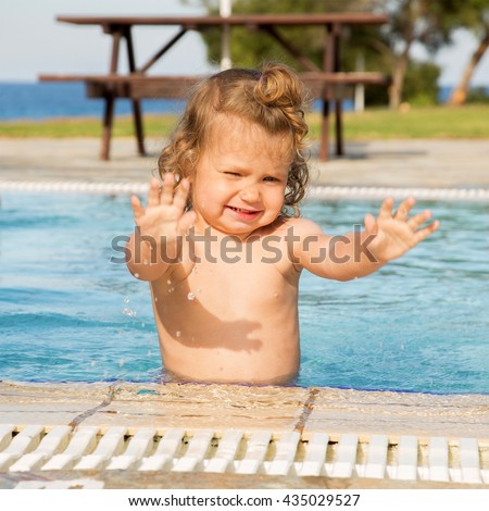 Little baby splashing water and playing in the pool. Summertime.