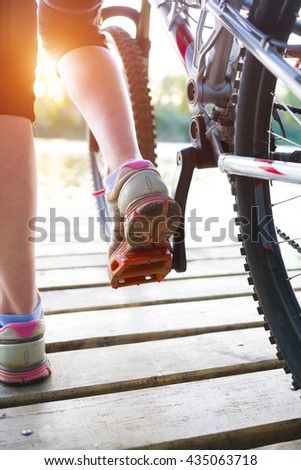 Girl with a Bicycle standing on the dock near the water and rest.