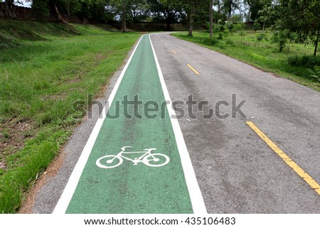 Separate bicycle lane on asphalt in the park. White bike symbol 