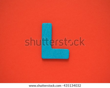 Capital Blue letter L from wood on red background.