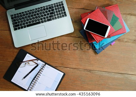office desk with laptop smart phone and business office background.,Layout of comfortable working space on wooden, internet laptop headphone phone notepad pen eyeglasses laying on it
