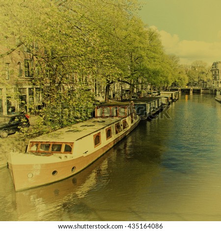 Beautiful city view with canal, houseboats and traditional houses, typical picture of canals in Amsterdam, Netherlands. Vintage film toned effect, square image