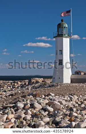 Historic Scituate lighthouse, with its uniquely constructed tower, along rocky harbor in Massachusetts.