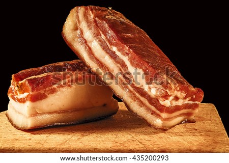 Two pieces of meaty smoked bacon home on a kitchen cutting board.                        