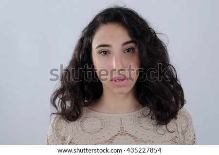 Young latin exotic girl wearing a beige sweater looking at camera