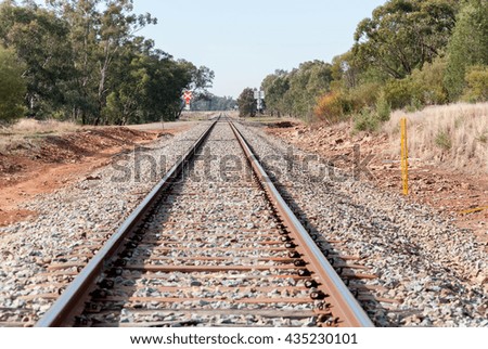 a straight stretch of railroad track with trees and crossing