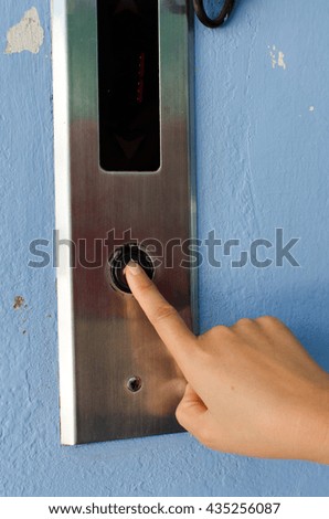 finger presses the elevator button.  hand reaches for the button of the elevator call.