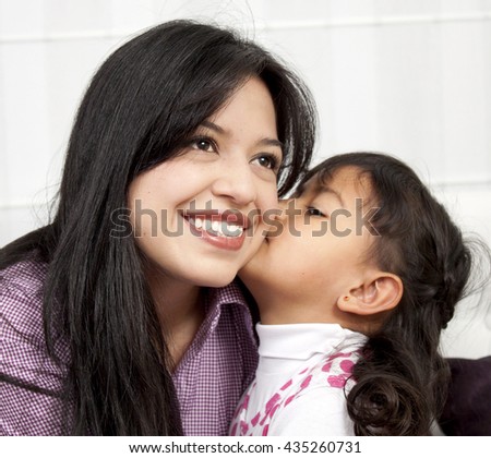 Little girl kissing her mommy in the home
