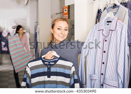 Glad blond girl shopping comfortable sleepwear for man in store