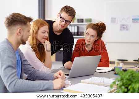 Four colleagues conducting business meeting using laptop computer in large office on sunny day Royalty-Free Stock Photo #435305407