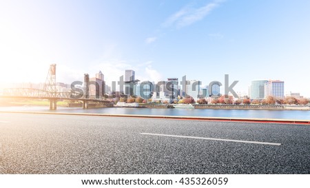 empty asphalt road near water with cityscape and skyline of portland at sunrise