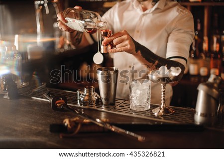 Bartender is adding ingredient in shaker at bar counter Royalty-Free Stock Photo #435326821