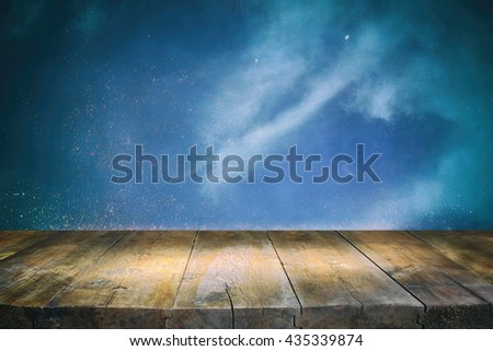 image of wooden table in front of glitter vintage lights background. blue, silver, purple and black. defocused.