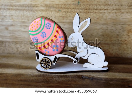 Wooden easter bunny rolling trolley with the varicolored easter egg on wooden background