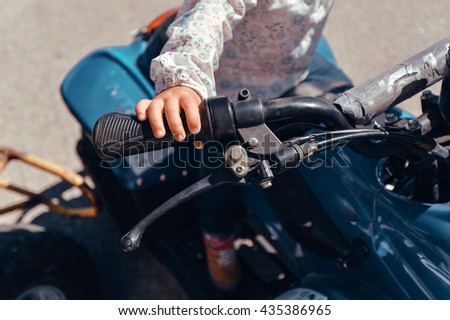 Closeup on small child riding a quad bike on sunny outdoors background, closeup 
