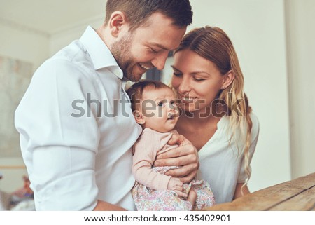 Proud mother and father smiling at their newborn baby daughter at home Royalty-Free Stock Photo #435402901