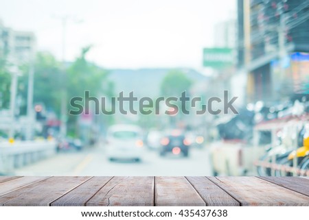 Wood table top on blur image of people driving car on day time for background usage.