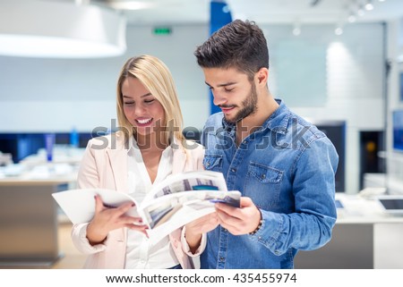 Attractive happy couple looking at a catalogue in a store. Royalty-Free Stock Photo #435455974