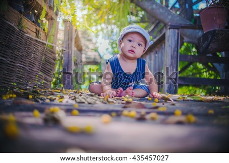 A portrait of the smiling baby boy playing outdoors with vignetting lens.