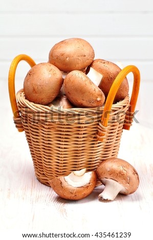 Organic mushrooms in a basket on white wooden background.