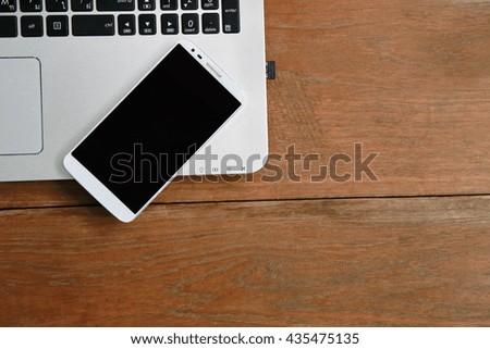 top view of laptop ,eyeglasses, notebook daily, phone on wood plank,Layout of comfortable working space on wooden, internet laptop headphone phone notepad pen eyeglasses laying on it
