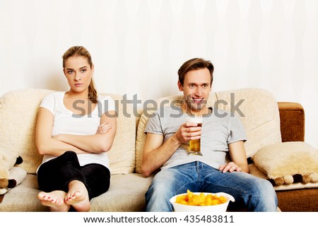 Woman sitting bored while man watching sports