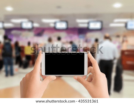 woman use mobile phone and blurred image of people are waiting at airport check-in counter