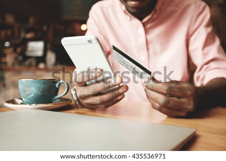 African American man in casual shirt paying with credit card online while making orders via the Internet. Successful black businessman making transaction using mobile bank application. Selective focus Royalty-Free Stock Photo #435536971