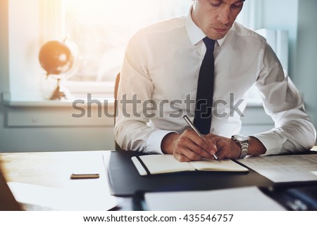 Close up of business man in shirt and tie working in his office writing in a classic note book Royalty-Free Stock Photo #435546757