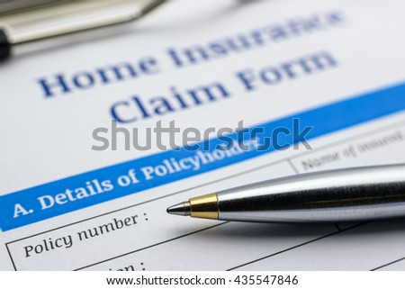 Blue ballpoint pen and a home insurance claim form on a clip board. A blank / empty form is waiting to be filled and signed by a policyholder / insured person.