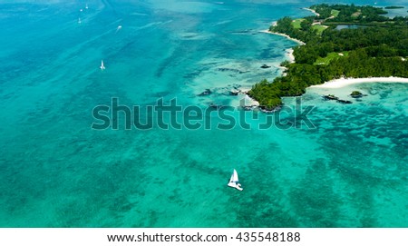 Aerial picture of the east coast of Mauritius Island. Beautiful lagoon of Mauritius Island shot from above. Catamaran boat sailing in turquoise lagoon
