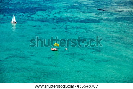 Aerial picture of the east coast of Mauritius Island. Beautiful lagoon of Mauritius Island shot from above. Catamaran boat sailing in turquoise lagoon and yellow parasailing getting ready to take off 