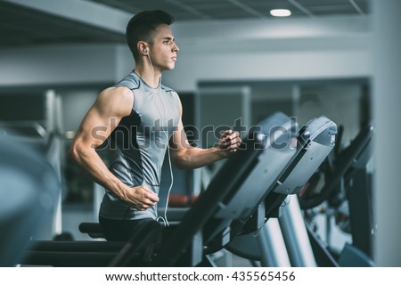 Young man in sportswear running on treadmill at gym Royalty-Free Stock Photo #435565456