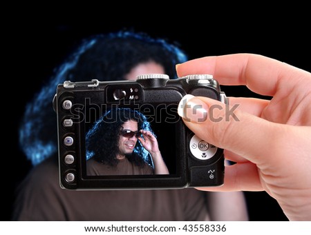 Taking a picture of an ethnic man looking cool with sunglasses as creative lighting lights up his long curly hair