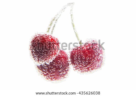 Cherry in water covered with bubbles on a white background