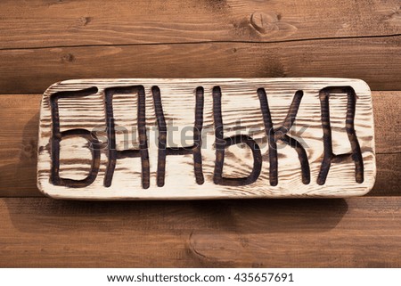 The inscription "bathhouse" (on russian language)on the plate on a wooden background