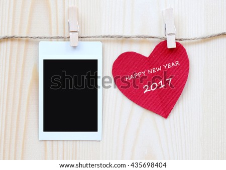Red fabric heart with happy new year 2017 word and blank instant photo hanging on the clothesline, new year template