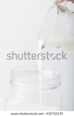 Milk pouring from a bottle in a glass isolated on a white background