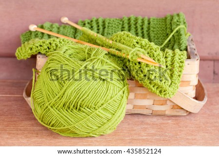 Yarn, knitting needles placed in the green basket.