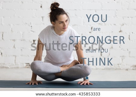 Beautiful young woman working out in loft interior, doing yoga exercise on blue mat. Motivational phrase "You are stronger than you think"