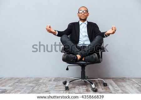 Relaxed handsome african young man sitting and meditating on office chair Royalty-Free Stock Photo #435866839