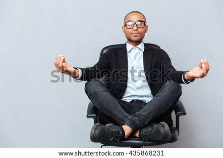 Closeup of attractive young man in glasses meditating on office chair
