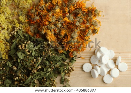 dried flowers healing herbs on wooden background with tablets