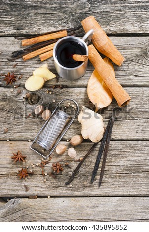 traditional mulled wine in purity steel mug and grater, spices on old wooden table