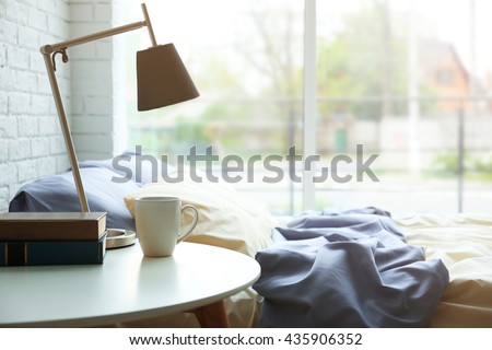 Lamp, books and cup on a side table Royalty-Free Stock Photo #435906352