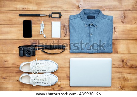 Travel concept shoes, shirt, mobile phone, laptop,mp3, usb, camera, selfie stick on the desk
