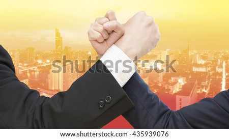 Double exposure image of business competitors doing arm wrestling.
